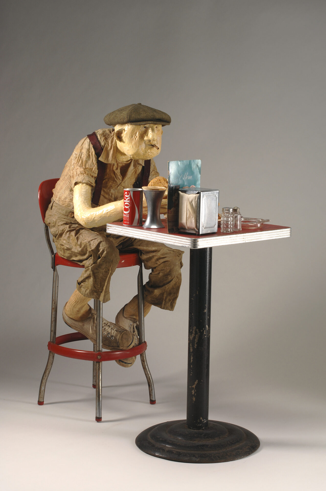 A miniature sculpture of an old man sitting down